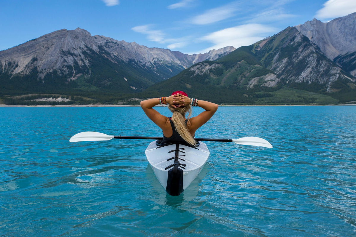 Kayaker paddling across open blue sea