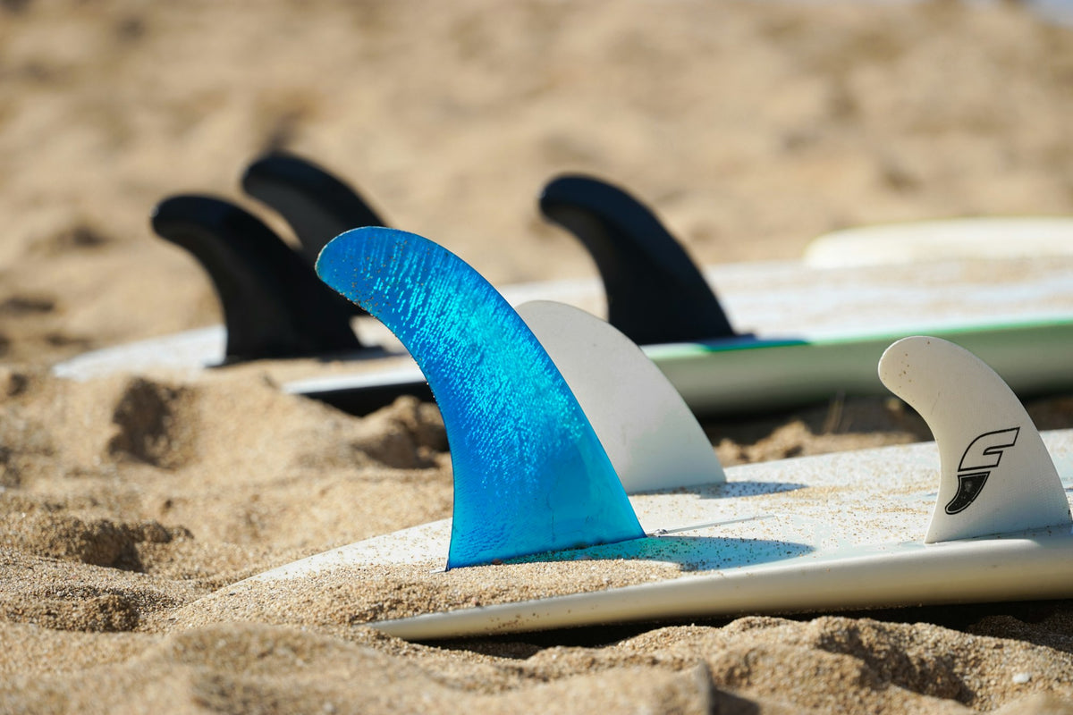 Close-up of two white surfboards lying on the sand