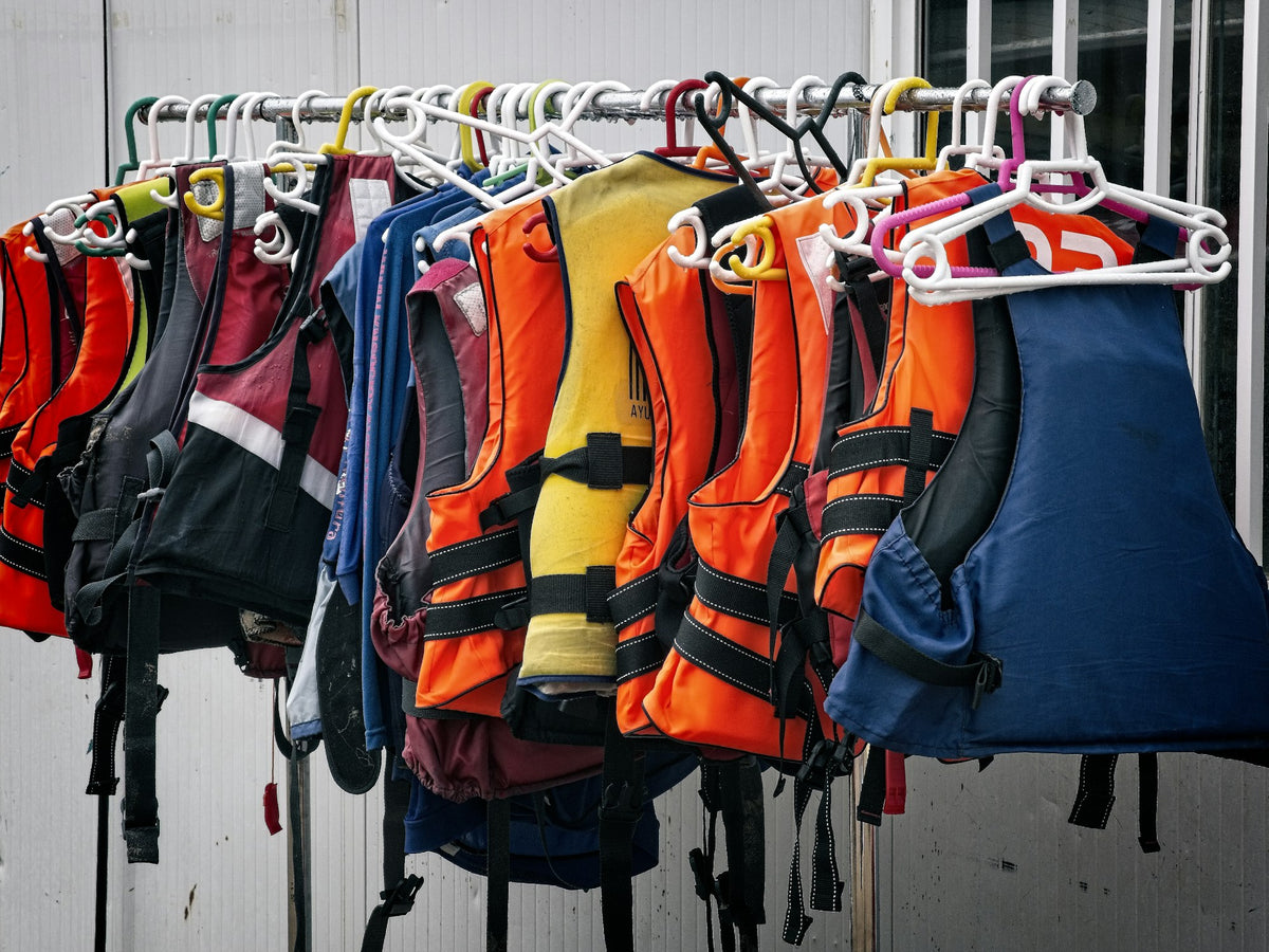 Assorted orange and red life jackets piled together