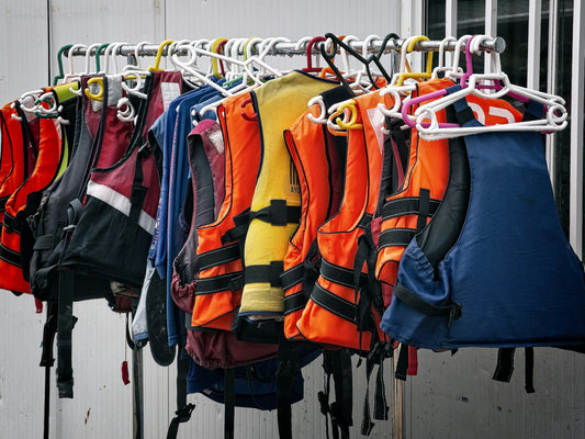 Assorted orange and red life jackets piled together