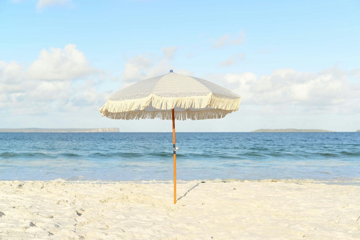 White beach umbrella planted in the sand at the edge of the sea
