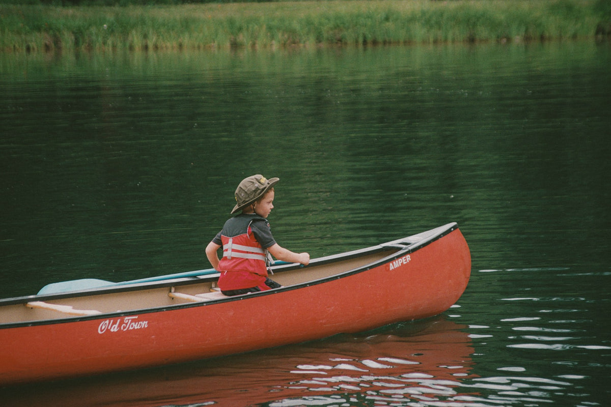 Paddler in a red life vest kayaking on a calm lake