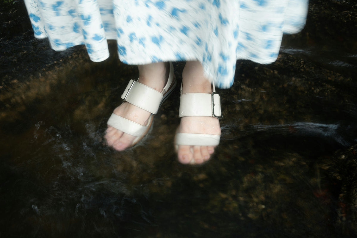 Feet in strapped water sandals wading through clear shallow water