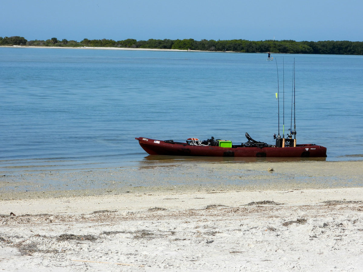 Fishing kayak rigged with rods in holders floating on calm water