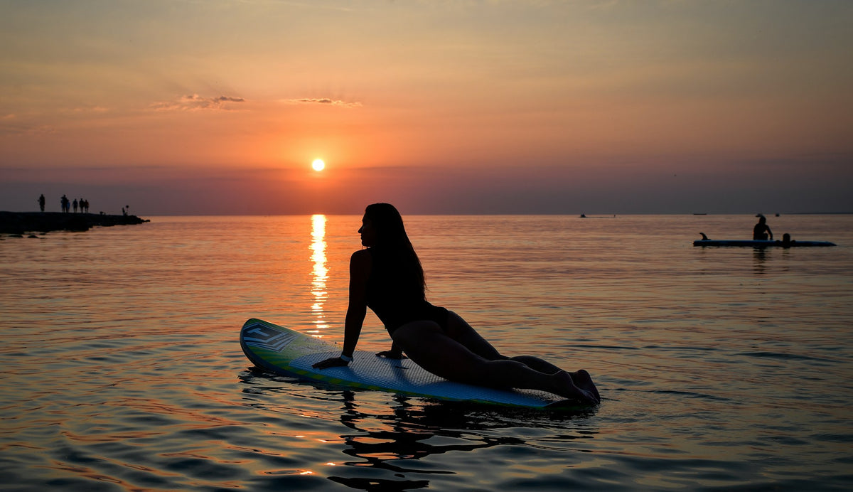 Woman holding a yoga pose on a stand-up paddleboard at sunset