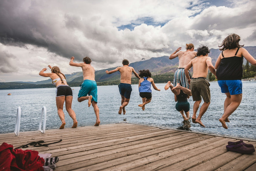 Friends jumping off a dock into the lake together