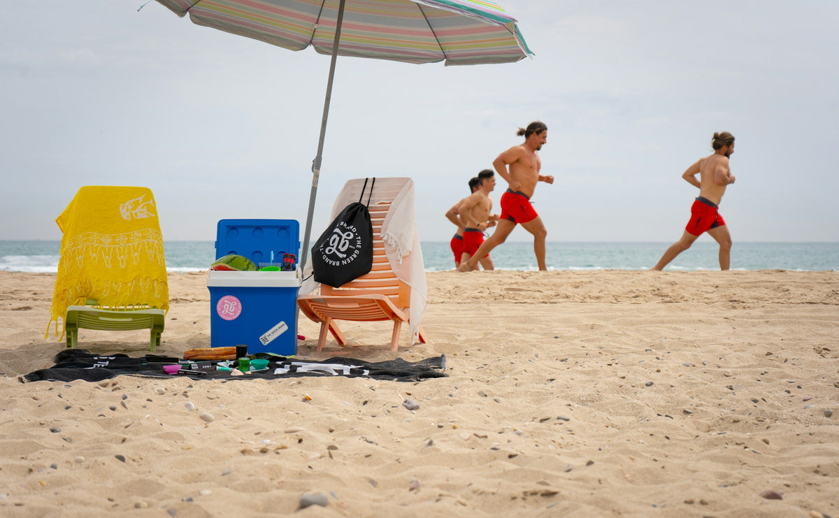 Beach setup with umbrella, cooler and chairs as friends head to the water
